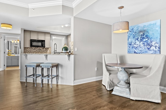 dining room featuring dark hardwood / wood-style floors, ornamental molding, and sink