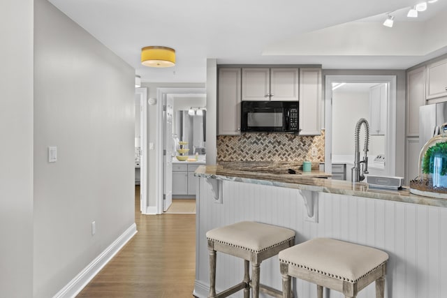 kitchen featuring gray cabinetry, a breakfast bar, light hardwood / wood-style floors, and tasteful backsplash