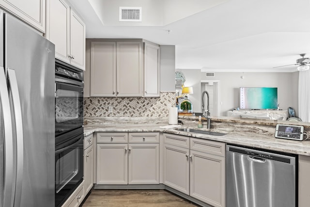 kitchen featuring sink, dark hardwood / wood-style floors, ceiling fan, light stone counters, and stainless steel appliances