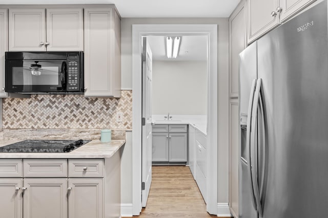 kitchen featuring sink, light hardwood / wood-style floors, gray cabinetry, and black appliances