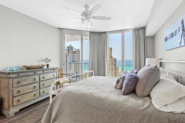 bedroom with access to outside, a water view, ceiling fan, and dark wood-type flooring