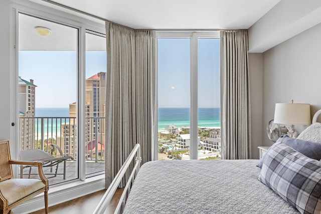 bedroom featuring a beach view, wood-type flooring, and a water view