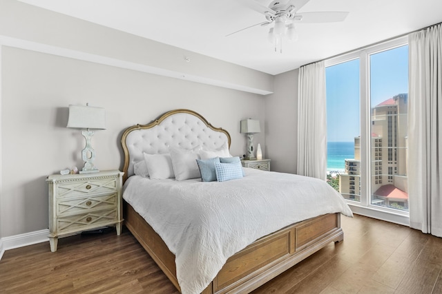 bedroom featuring ceiling fan, dark hardwood / wood-style flooring, and a water view