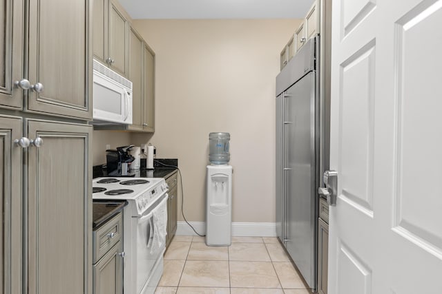 kitchen featuring light tile patterned floors, white appliances, and dark stone countertops