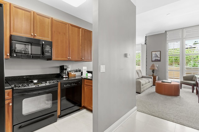 kitchen featuring light tile patterned floors, dark stone counters, and black appliances