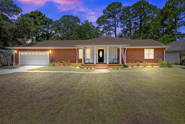 ranch-style house featuring a yard, a garage, and a porch