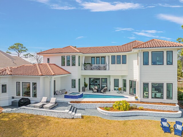 back of property with a yard, a patio area, a balcony, and a pool with hot tub