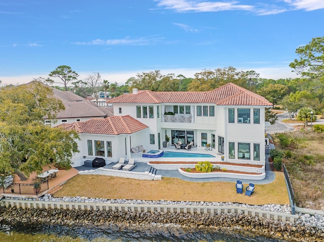 rear view of property with a balcony, a water view, and a patio