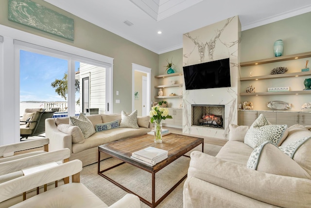 living room with ornamental molding and a high end fireplace