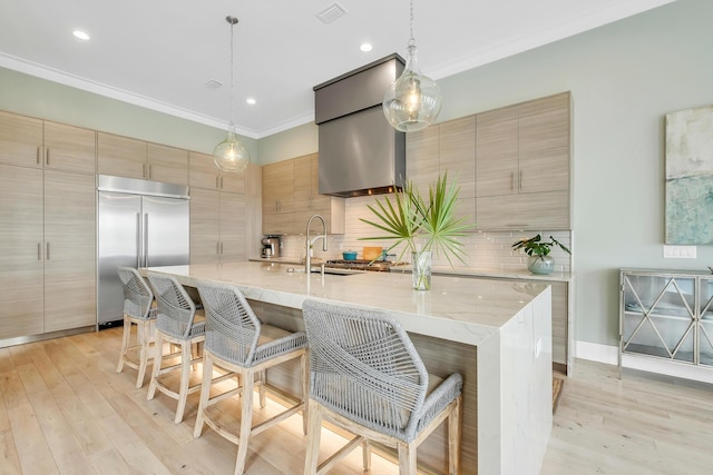 kitchen with stainless steel built in refrigerator, pendant lighting, a breakfast bar, and an island with sink