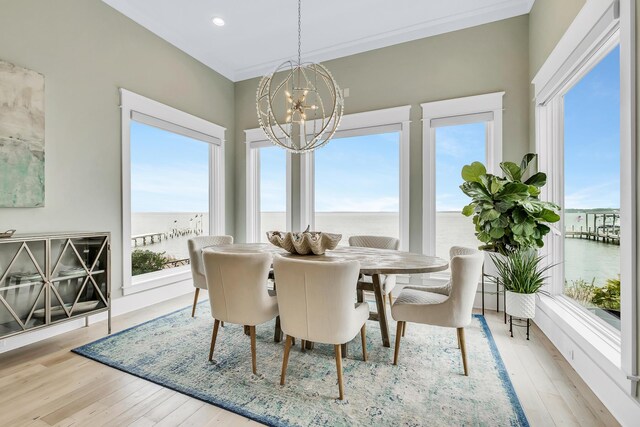 dining space with a chandelier, a water view, light hardwood / wood-style flooring, and a healthy amount of sunlight