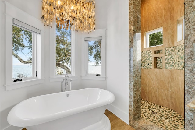 bathroom featuring a notable chandelier, a water view, wood-type flooring, and independent shower and bath