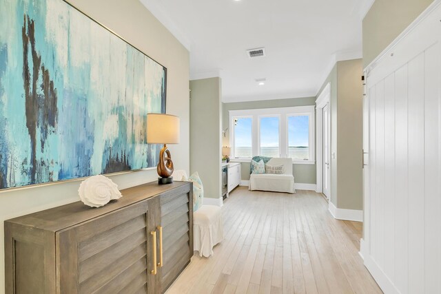 hallway with light hardwood / wood-style floors and crown molding