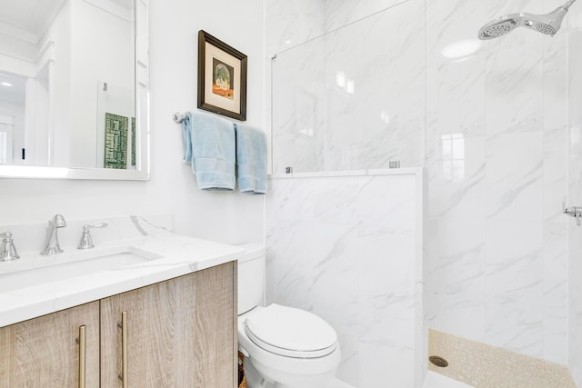 bathroom with toilet, vanity, and tiled shower