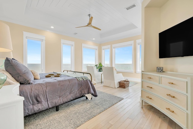 bedroom featuring a raised ceiling, ceiling fan, and light hardwood / wood-style flooring