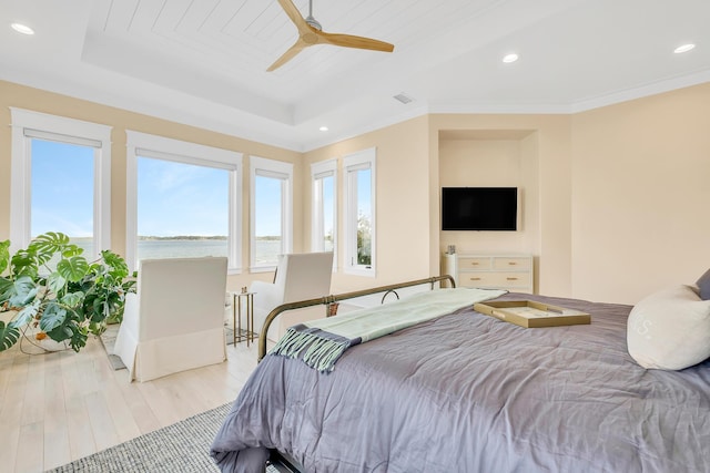 bedroom with a tray ceiling, light hardwood / wood-style flooring, ceiling fan, and crown molding