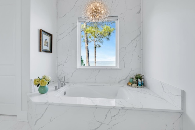 bathroom featuring a chandelier, a healthy amount of sunlight, and a tub