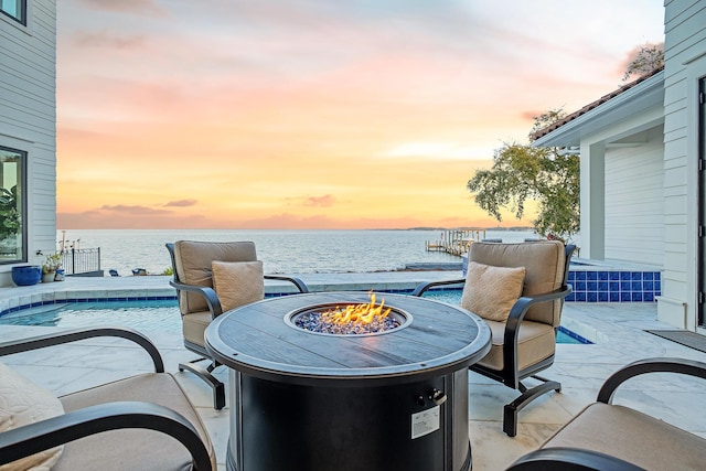 patio terrace at dusk with a water view and an outdoor fire pit