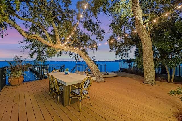 deck at dusk featuring a water view