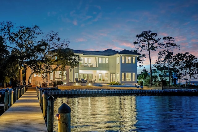 back house at dusk with a balcony and a water view