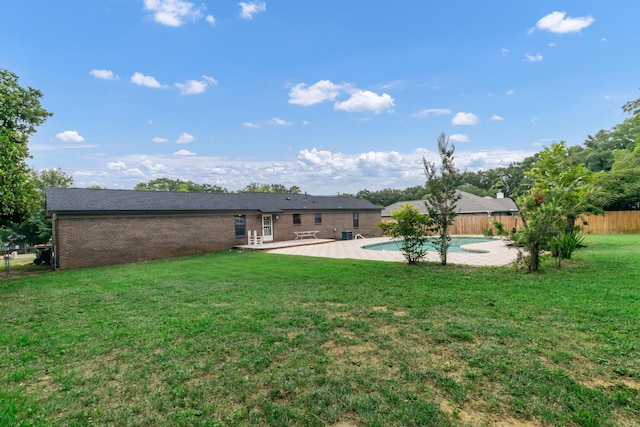 back of house with a fenced in pool, a lawn, and a patio