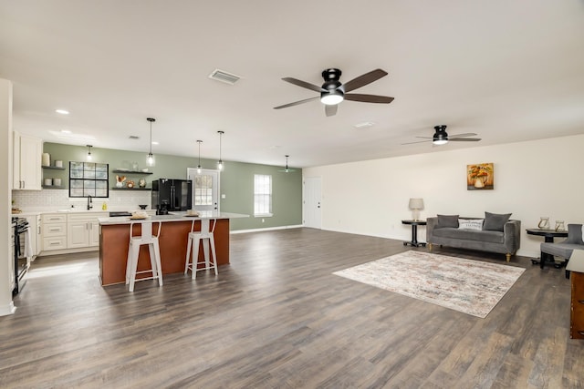 living room featuring sink, dark wood-type flooring, and ceiling fan