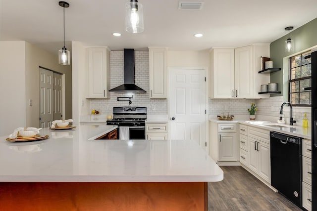 kitchen featuring sink, gas range, dishwasher, pendant lighting, and wall chimney range hood