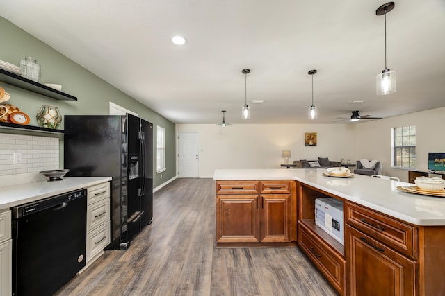 kitchen with dark wood-type flooring, ceiling fan, hanging light fixtures, tasteful backsplash, and black appliances