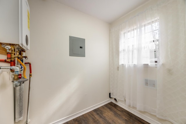 laundry room with dark hardwood / wood-style flooring, electric panel, and water heater