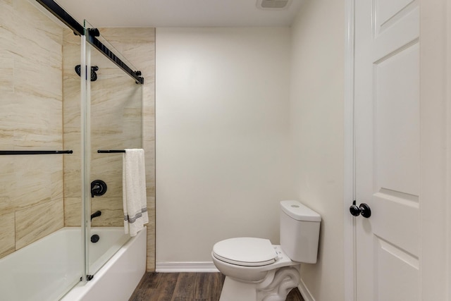 bathroom featuring combined bath / shower with glass door, hardwood / wood-style floors, and toilet