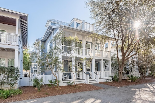 view of front of property with metal roof, fence, and a balcony