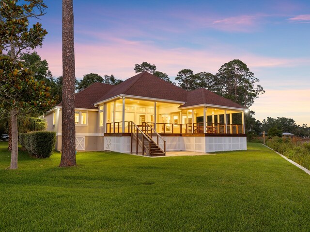 back house at dusk with a lawn