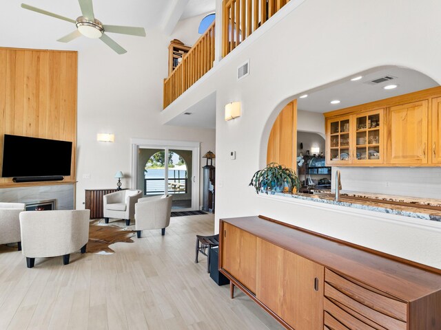 kitchen featuring ceiling fan, light hardwood / wood-style floors, and a towering ceiling