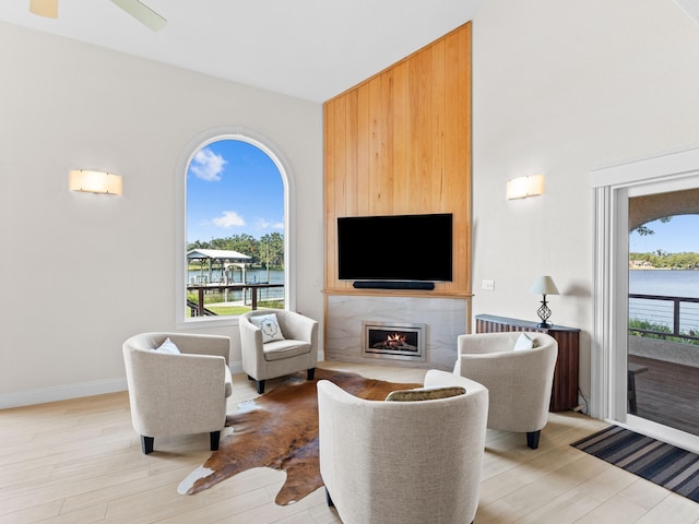 living room featuring a water view, ceiling fan, light hardwood / wood-style floors, and a fireplace