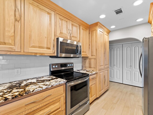 kitchen featuring tasteful backsplash, stainless steel appliances, light wood-type flooring, light brown cabinetry, and light stone counters