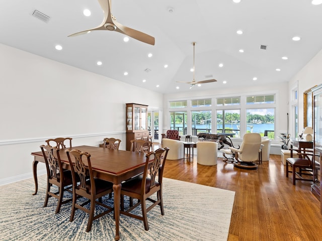 dining space featuring high vaulted ceiling, ceiling fan, a water view, and hardwood / wood-style floors