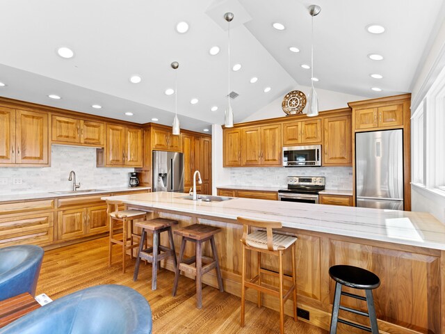 kitchen with sink, light hardwood / wood-style floors, vaulted ceiling, and appliances with stainless steel finishes