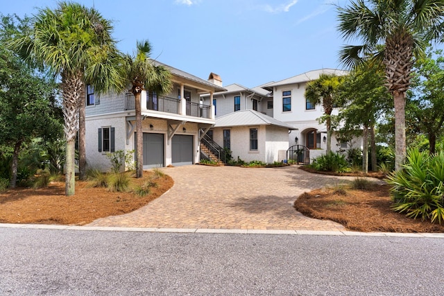 view of front facade featuring stucco siding, driveway, a gate, an attached garage, and a chimney