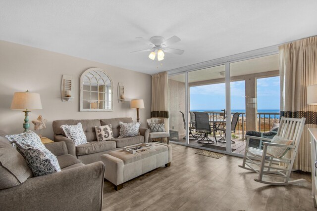 living room with hardwood / wood-style floors, a water view, floor to ceiling windows, and ceiling fan