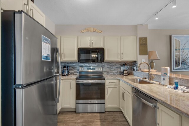 kitchen featuring dark hardwood / wood-style flooring, sink, appliances with stainless steel finishes, tasteful backsplash, and light stone countertops