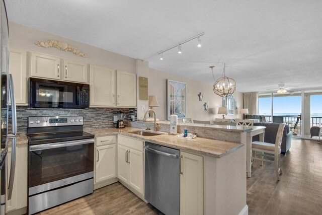 kitchen with appliances with stainless steel finishes, tasteful backsplash, sink, kitchen peninsula, and light stone counters