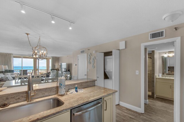 kitchen featuring light hardwood / wood-style floors, sink, stacked washer and clothes dryer, light stone counters, and stainless steel dishwasher