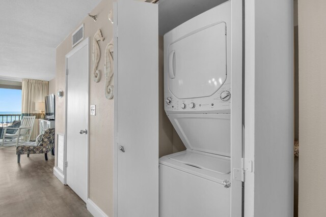 washroom with hardwood / wood-style floors and stacked washer and dryer