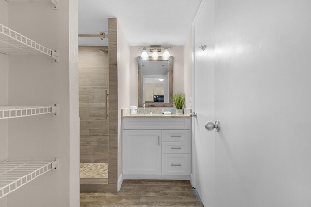 bathroom featuring hardwood / wood-style floors, tiled shower, and vanity