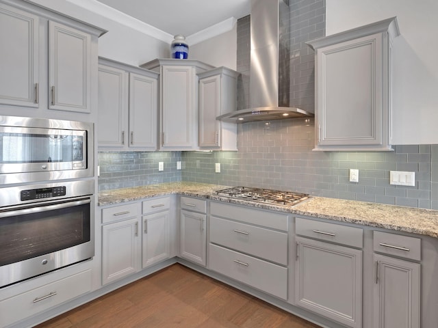 kitchen featuring appliances with stainless steel finishes, backsplash, light hardwood / wood-style flooring, and wall chimney exhaust hood