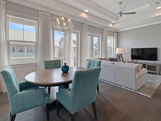 dining space featuring ceiling fan with notable chandelier, a tray ceiling, plenty of natural light, and dark hardwood / wood-style floors