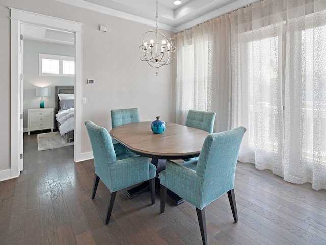 dining area featuring a raised ceiling, dark hardwood / wood-style flooring, and an inviting chandelier