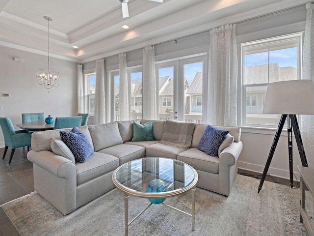 living room featuring hardwood / wood-style floors, a notable chandelier, a raised ceiling, and crown molding