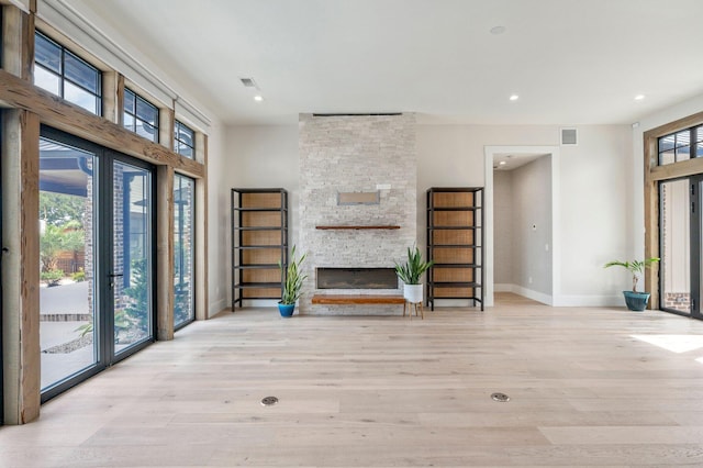 unfurnished living room featuring a healthy amount of sunlight, light wood-type flooring, and a fireplace