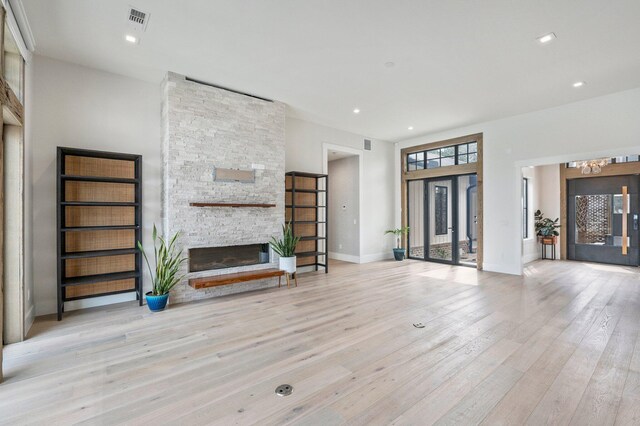 unfurnished living room featuring a stone fireplace and light wood-type flooring